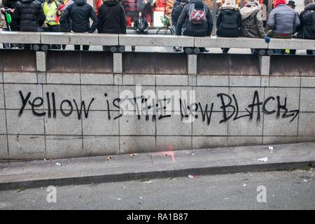 Grafitti: "Gelb ist das neue Schwarz" Während des Protestes gesehen. Gelbe weste Demonstranten versammelt und marschierten auf den Straßen von Paris ein weiteres Samstag auf, was Sie die Akte VII gegen die Politik der französische Präsident Emmanuel's Längestrich nennen. Stockfoto