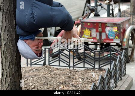 New York, USA. 30. Dez, 2018. Auf den ersten, Sie ihn hören, dann sehen Sie Larry Cohen von Huntington, Long Island, New York, nur um hing kopfüber an einem Baum, spielen seine Flöte während des Zeichnens starrt, Kommentare und Spenden von Passanten bei Besetzt 34 th. Straße in Manhattan am 30. Dezember 2018. © 2018 G. Ronald Lopez/DigiPixsAgain. us/AlamyLive Nachrichten Stockfoto