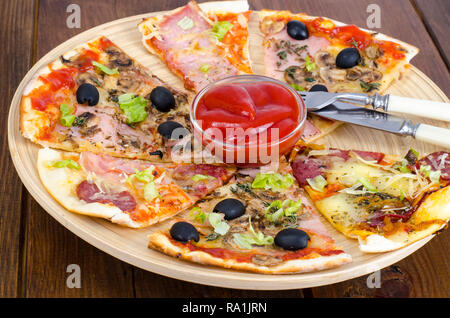 Sechs Scheiben Pizza mit verschiedenen Toppings auf Holzbrett. Studio Foto Stockfoto