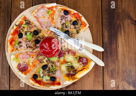 Sechs Scheiben Pizza mit verschiedenen Toppings auf Holzbrett. Studio Foto Stockfoto