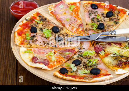 Sechs Scheiben Pizza mit verschiedenen Toppings auf Holzbrett. Studio Foto Stockfoto