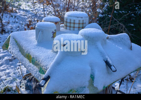 Gefrorene Alten rostigen Metall Aufläufe auf einem Tisch unter dem Schnee im Winter. In der Nähe fotografiert im Winter Stockfoto