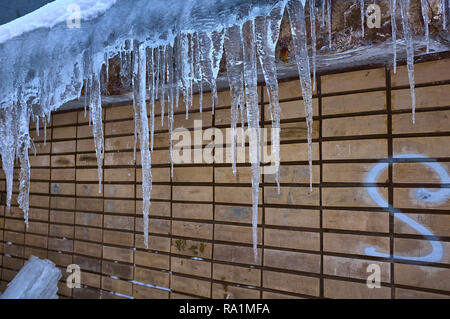 Eiszapfen hängen von dem Dach des alten Hauses, im späten Winter oder frühen Frühling. Und es ist ein Buchstabe S wie ein Santa anmelden Stockfoto