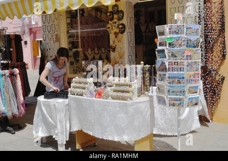 Ein Shop Assistant ordnet eine externe Anzeige auf Burano, einer Insel in der Lagune von Venedig, Italien. Stockfoto