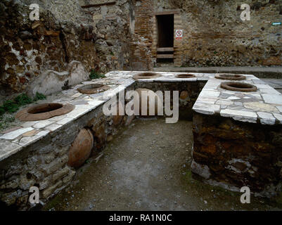 Italien. Herculaneum. Alte römische Stadt, die vom Ausbruch des Vesuv im Jahr 79 N.CHR. zerstört. Counter Bar mit Löchern, wo Gläser (dolia) für essen oder Wein eingestellt wurden. Kampanien. Stockfoto