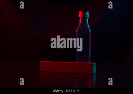 Kleine Flasche Alkohol im Neonlicht Stockfoto