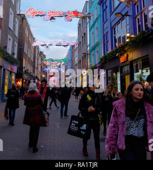 Käufer auf Carnaby Street, Soho, London unter Weihnachten Neon Licht Installation. Dezember 2018 Stockfoto