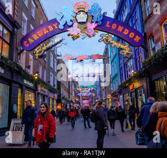 Queen's crest auf die Carnaby Bogen mit iconic lyrics Freddie Mercury manifestiert in schwindelerregende neon Weihnachtsbeleuchtung auf Carnaby Street, London, 2018 Stockfoto