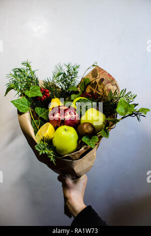 Einzigartige festlichen Blumenstrauß aus Äpfeln, Birnen, Pflaumen, Grapefruits und blühenden Rosen in den Händen eines Mädchens Stockfoto