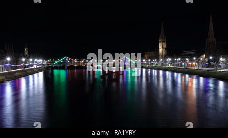 Schöne vor Weihnachten abends zu Fuß in Inverness, Schottland. Schöne Weihnachten Lichter und Riverside am Fluss Ness. Alte Kirche im Hintergrund Stockfoto