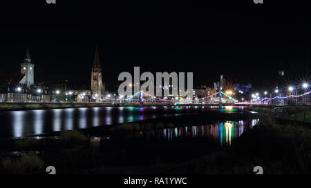 Schöne vor Weihnachten abends zu Fuß in Inverness, Schottland. Schöne Weihnachten Lichter und Riverside am Fluss Ness. Alte Kirche im Hintergrund Stockfoto