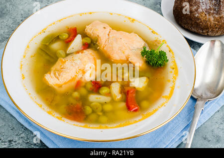 Fischsuppe mit Gemüse und Lachs in weiße Platte auf grauem Hintergrund. Studio Foto Stockfoto