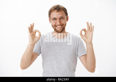 Alles unter Kontrolle vertrauen Sie mir. Portrait von Ihnen freundlich und selbstbewusst aussehenden bärtigen Mann in Gläser heben beide Hände auf okay oder hervorragende geste Sicherstellung der Arbeit Lächeln wird in der Zeit Stockfoto