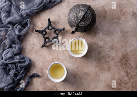 Stillleben mit traditioneller asiatischer Kräutertee, in einem alten Cast gekocht - Bügeleisen Wasserkocher auf einen strukturierten Hintergrund. Flach. Stockfoto