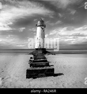 Ein altes weißes Licht Haus mit einem hellen roten Dach sitzt auf einem Sandstrand mit einem Steinweg infront ist das Meer in der Ferne und einen großen blauen Himmel w Stockfoto