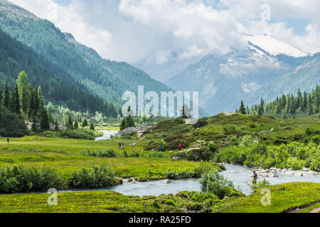 Die Menschen wandern in die Entfernung entlang einer alpinen Fluss Stockfoto