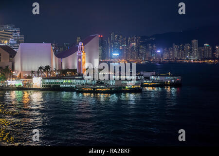 Die Tsim Sha Tsui Star Ferry Piers bei Nacht mit Blick auf den Uhrturm und kulturelles Zentrum, und über die Causeway Bay auf Hong Kong Island Stockfoto