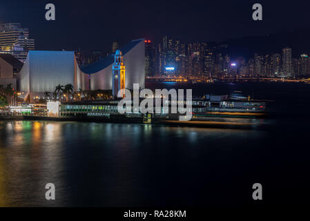 Die Tsim Sha Tsui Star Ferry Piers bei Nacht mit Blick auf den Uhrturm und kulturelles Zentrum, und über die Causeway Bay auf Hong Kong Island Stockfoto