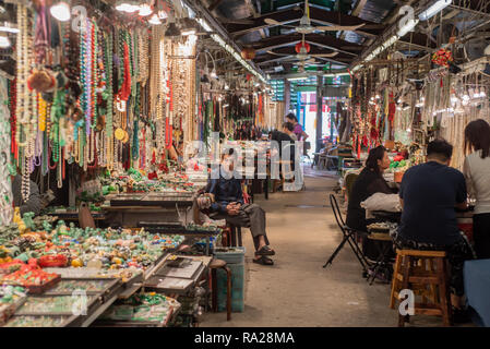 Abschaltdruck Inhaber bei Hong Kong's berühmten Jade Markt mit ihren bunten Displays von Jade Armbänder, Perlen und Schmuckstücke. Stockfoto