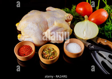 Mariniertes rohes Huhn bereit zum Grillen auf einem dunklen Hintergrund. Rohes Huhn und Gemüse Stockfoto