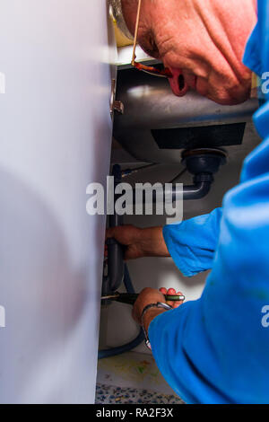 Professionelle Heimwerker arbeitet mit pilers und Befestigung der Leitung am Becken Stockfoto