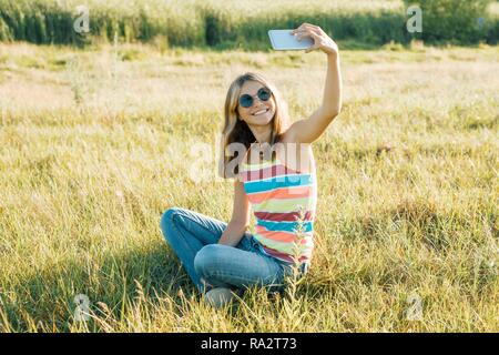 Junge Mädchen blogger nimmt Fotos und Videos für sein Blog. Mädchen lächelnd auf den Sommer City Park. Stockfoto