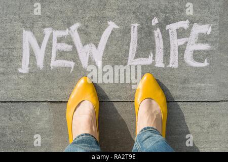 Weibliche Füße mit Text neues Leben auf grau Bürgersteig geschrieben. Stockfoto