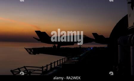 Ein US Marine Corps B F-35 Lightning II Stealth Fighter Aircraft ist von der aufgehenden Sonne silhouetted, wie es das Flight Deck der Wasp aufgehoben Klasse amphibisches Schiff USS Essex während Operationen Dezember 30, 2018 in den Arabischen Golf. Stockfoto