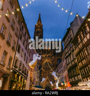 Beleuchteten Kathedrale von Straßburg mit Weihnachtsschmuck auf der anderen Straßenseite bei Nacht hängen, Elsass, Frankreich. Stockfoto