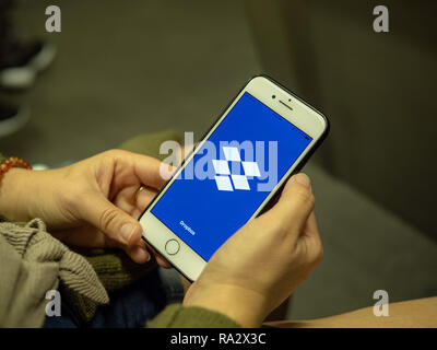 Frau Eröffnung Dropbox App mit Logo auf dem Bildschirm des iPhone beim Pendeln auf der U-Bahn Stockfoto