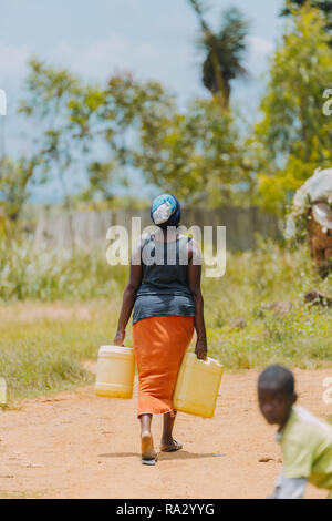Frau, die Wasser in Entebbe, Uganda, trägt Stockfoto