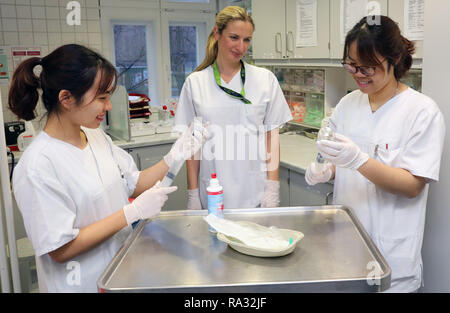 Rostock, Deutschland. 21 Dez, 2018. Als Huyen Nguyen Thi (l) und Anh Tu Tun (r), Vietnamesisch Krankenschwestern in der Ausbildung, werden in ihrer Arbeit in der Onkologie von Janine Schreiber begleitet, Leiter Krankenschwester. 16 Frauen und 4 Männer aus Vietnam begann die Ausbildung in der Krankenpflege in der universitären Medizin an der Ende August 2018. Wie erwartet, der Umgang mit der Deutschen Sprache ist immer noch schwierig, aber von der technischen Seite gibt es keine Probleme. Quelle: Bernd Wüstneck/dpa/Alamy leben Nachrichten Stockfoto