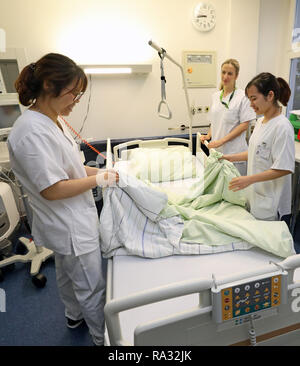 Rostock, Deutschland. 21 Dez, 2018. Anh Tu Tun (l) und Thi als Huyen Nguyen (r), Vietnamesisch Krankenschwestern in der Ausbildung, in ihrer Arbeit in der Onkologie von Janine Schreiber begleitet werden, Leiter Krankenschwester. 16 Frauen und 4 Männer aus Vietnam begann die Ausbildung in der Krankenpflege in der universitären Medizin an der Ende August 2018. Wie erwartet, der Umgang mit der Deutschen Sprache ist immer noch schwierig, aber von der technischen Seite gibt es keine Probleme. Quelle: Bernd Wüstneck/dpa/Alamy leben Nachrichten Stockfoto