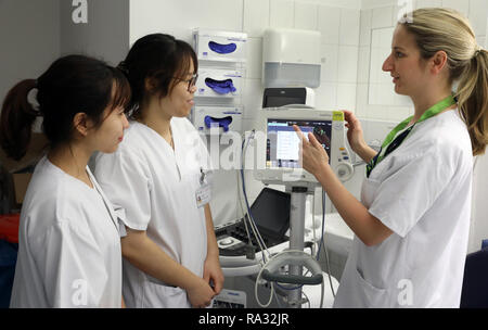 Rostock, Deutschland. 21 Dez, 2018. Als Huyen Nguyen Thi (L-R) und Anh tu tun, Vietnamesisch Krankenschwestern in der Ausbildung, die für die ärztliche Überwachung von Janine Schreiber, Senior Gesundheit und Krankenpflege Krankenschwester in der Onkologie angewiesen. 16 Frauen und 4 Männer aus Vietnam begann die Ausbildung in der Krankenpflege in der universitären Medizin an der Ende August 2018. Wie erwartet, der Umgang mit der Deutschen Sprache ist immer noch schwierig, aber von der technischen Seite gibt es keine Probleme. Quelle: Bernd Wüstneck/dpa/Alamy leben Nachrichten Stockfoto