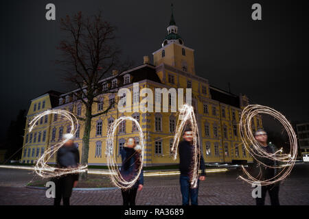 Oldenburg, Deutschland. 31 Dez, 2018. Am Silvesterabend, vier Personen stehen vor dem Oldenburger Schloss und schreiben das Jahr 2019 mit brennenden Wunderkerzen (lange Belichtungszeit). Credit: mohssen Assanimoghaddam/dpa/Alamy leben Nachrichten Stockfoto