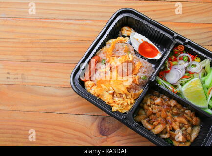 Gebratener Reis mit Garnelen paste gehören Mango, Eier, Schweinefleisch, Zwiebeln, Gemüse in Box schwarz/Thai Essen auf einem Holz Tisch Hintergrund Stockfoto