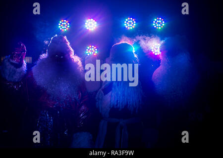 Drei glückliche senior Santa Claus Zahlen im Licht der Lampen Stockfoto