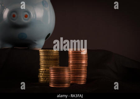 Finanzen und Banking Konzept. Sparschwein mit gestapelten Münzen und einen dunklen Hintergrund. Stockfoto