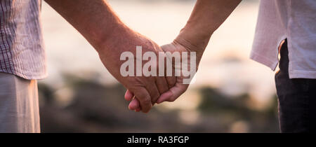 Valentinstag Liebe über Zeit Konzept mit Hände von Mann und Frau reife alte Menschen zusammen, die einander mit defokussiertem Hintergrund-Roman Stockfoto