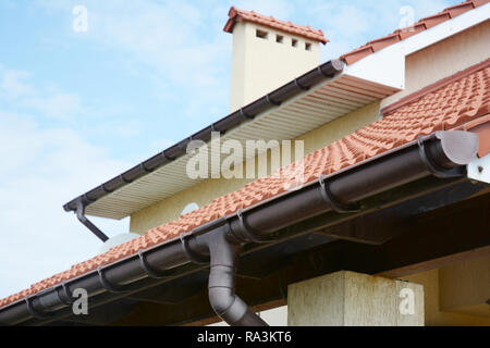 Regenrinnen System ein neues Haus mit Kamin, roter Ton Ziegeldach und Giebel und Tal Art der Dachkonstruktion Stockfoto