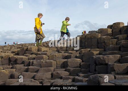 Touristen zu Fuß auf die Basaltsäulen, Giant's Causeway, Causeway Coast, County Antrim, Nordirland, Großbritannien Stockfoto