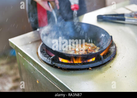 Kochen im Freien asiatische Speisen in einem Wok auf dem Gasherd closeup Stockfoto