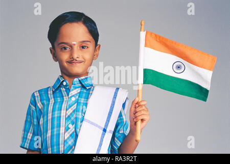 South Indian Boy gekleidet in der Tracht, das Tragen einer falschen Schnurrbart, halten Sie die indische Flagge Stockfoto