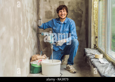Junge männliche Maler knetet putty mit Wasser in einem Eimer mit einem Handmixer für Gebäude vereint Stockfoto