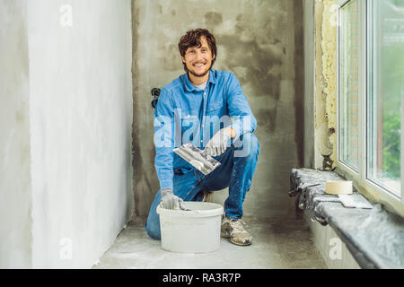 Master ist die Anwendung weiß putty an einer Wand und Verschmieren von Spachtel in einem Zimmer renovieren Haus tagsüber Stockfoto