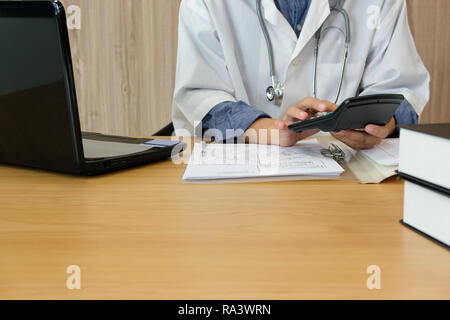 Arzt Arzt mit Stethoskop berechnen medizinische Gebühr Kosten und Erträge. Praktiker nutzen Taschenrechner an der Klinik Krankenhaus. Stockfoto