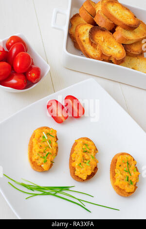 Weiße Platte mit Toast und Rührei, Schnittlauch Kräuter und Kirschtomaten auf weißem Hintergrund. Gegrilltes Brot mit Rührei und vegitable Stockfoto