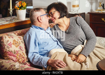 Porträt eines lächelnden liebevolle ältere Paar auf der Couch zu Hause sitzen Stockfoto