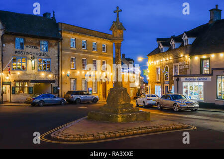 Die beleuchtete Marktplatz und steinernen Kreuz in der Nacht in der Stadt in den Cotswolds Stow auf der Wold Gloucestershire England Großbritannien Stockfoto