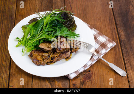 Scheiben von gebratene Leber, grüne Blätter von Salaten. Studio Foto Stockfoto